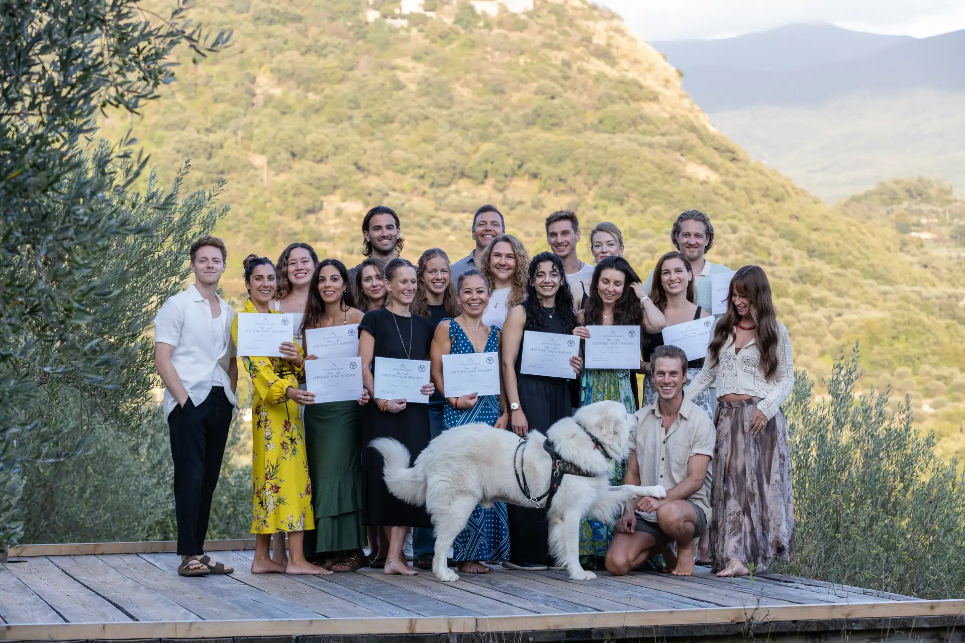 A newly certified teacher-training cohort holding their certificates on a Tuscan terrace
