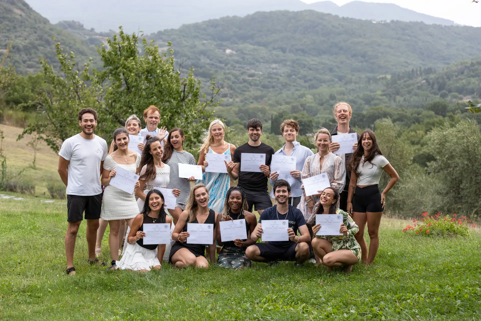 A graduating cohort gathered on the lawn with their certificates