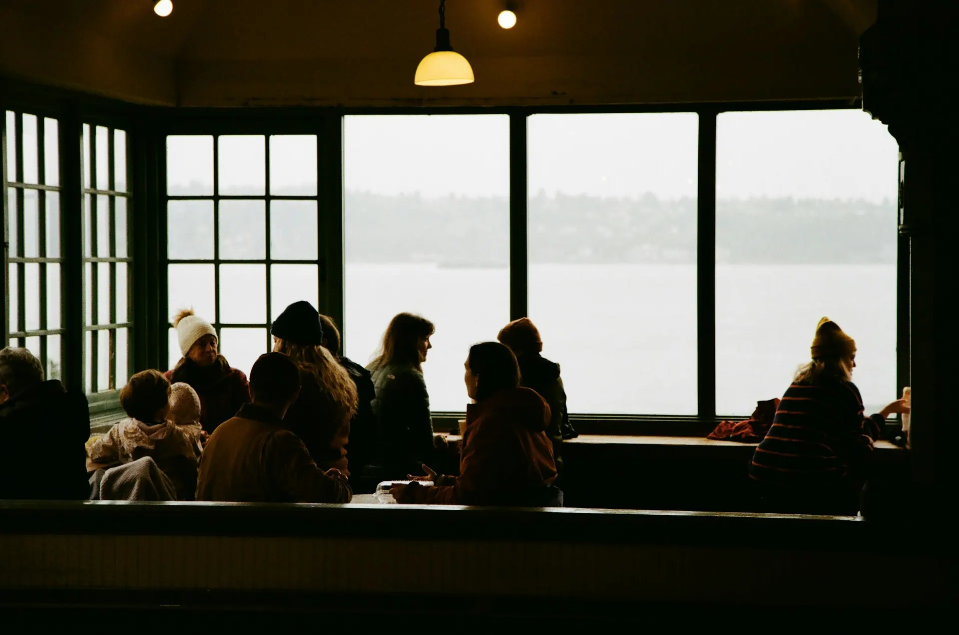 A meditation group silhouetted by a large window overlooking the water