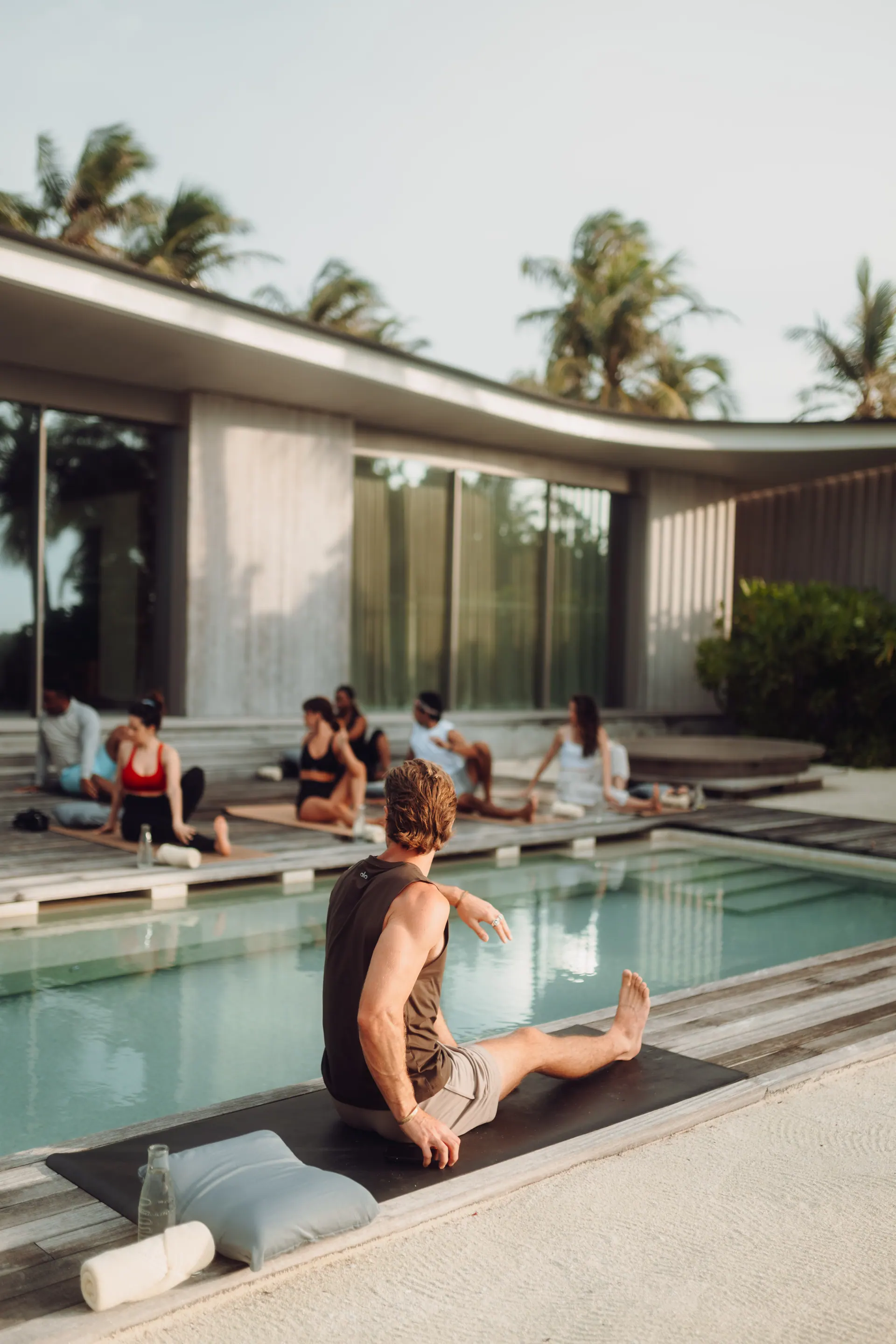 A morning class practicing on platforms around a still pool